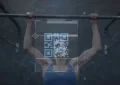 Pulling fit woman in blue sleeveless top gripping metal pull-up bar at gym, showing QR-code overlay